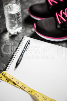 Notepad, measuring tape, shoes and bottle