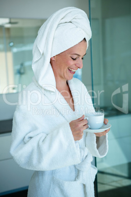 smiling woman in a dressing gown holding a cup and saucer