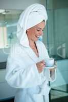 smiling woman in a dressing gown holding a cup and saucer