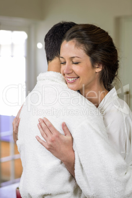 Young couple in bathrobe cuddling each other