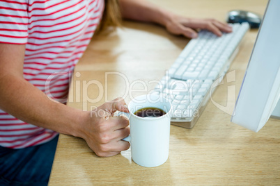 female hands holding a coffee cup and typing