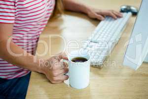 female hands holding a coffee cup and typing