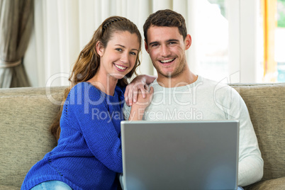 Young couple sitting on sofa and using laptop