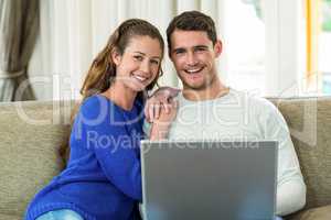 Young couple sitting on sofa and using laptop
