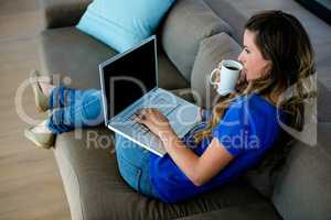 business woman typing on her laptop and sipping coffee