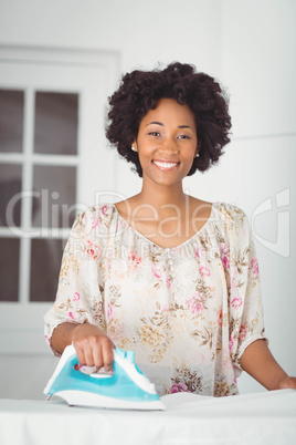 Smiling woman ironing in the kitchen