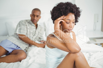 Upset woman sitting on bed after argument