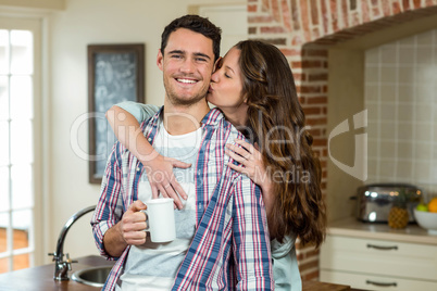 Woman kissing man from behind while having coffee