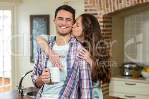 Woman kissing man from behind while having coffee