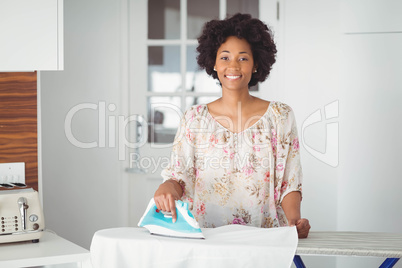 Smiling woman ironing in the kitchen