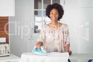 Smiling woman ironing in the kitchen