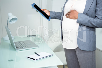 Pregnant businesswoman looking at tablet