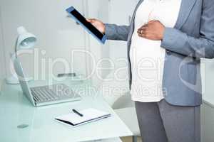 Pregnant businesswoman looking at tablet