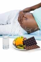 Pregnant woman lying by fruits and chocolates