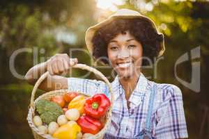 Smiling woman showing a basket of vegetables