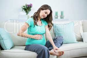 Pregnant woman massaging her tired feet
