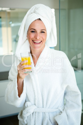 woman wearing a dressing gown drinking a glass of juice