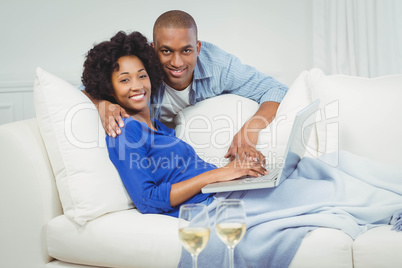 Happy couple on the sofa using laptop