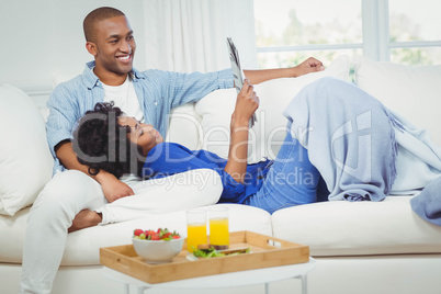 Smiling couple on the sofa reading newspaper