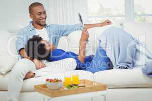 Smiling couple on the sofa reading newspaper