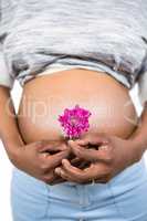 Pregnant woman with flower touching her belly