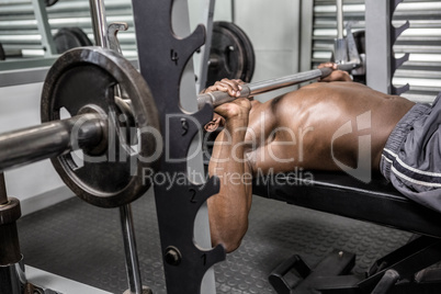 Shirtless man lifting barbell on bench