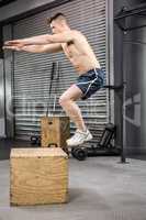 Shirtless man jumping on wooden block