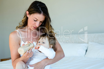 thoughtful woman bottle feeding a baby