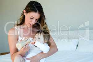 thoughtful woman bottle feeding a baby