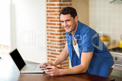 Young man using laptop in kitchen