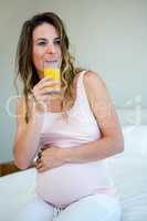 tired pregnant woman drinking orange juice