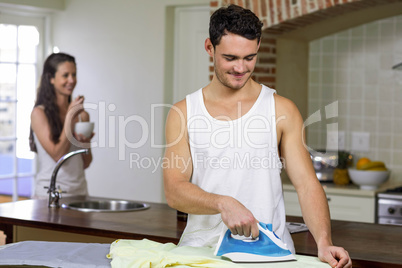 Man ironing a shirt in kitchen