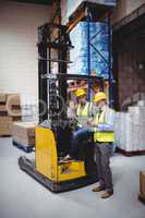 Warehouse worker talking with forklift driver