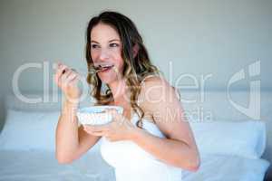 smiling woman eating a bowl of cereal