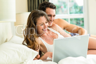 Young couple using laptop on bed