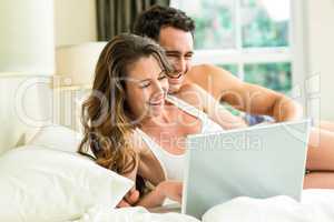 Young couple using laptop on bed