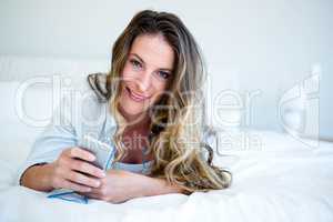 smiling woman lying on her bed listening to music