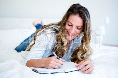 woman lying on her bed writing in a book