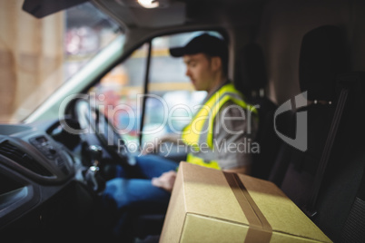 Delivery driver driving van with parcels on seat
