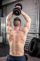 Shirtless man lifting heavy dumbbell