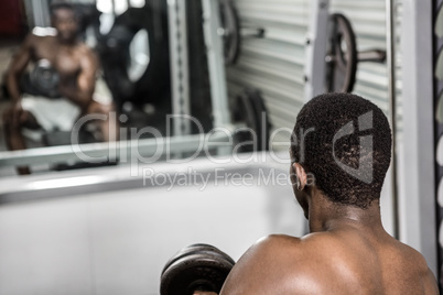 Shirtless man lifting dumbbell on bench