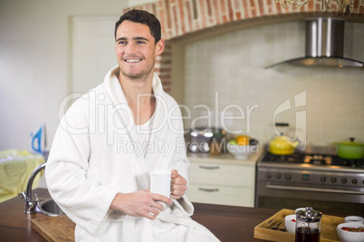 Young man in bathrobe holding a cup of tea