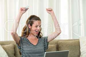 Excited young woman shopping online with a credit card