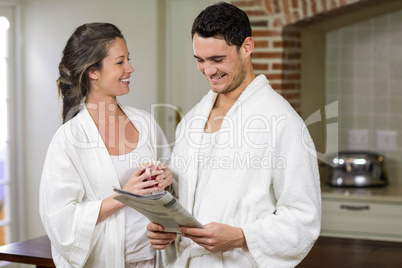 Happy couple in bathrobe reading newspaper