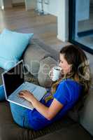 business woman sipping coffee and typing on her laptop