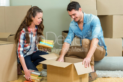 Young couple unpacking carton boxes in their new house