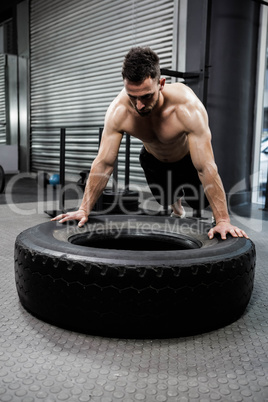 Shirtless man flipping heavy tire