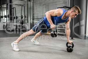 Muscular man doing push up with kettlebells