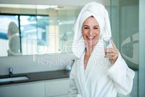 woman wearing a dressing gown drinking a glass of water