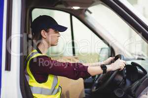 Delivery driver driving van with parcels on seat